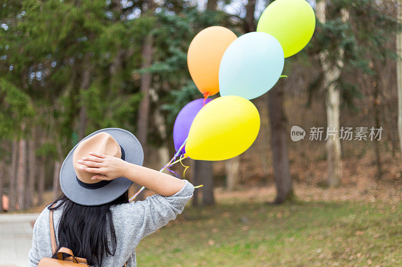 年轻女子拿着气球，享受她的自由时间