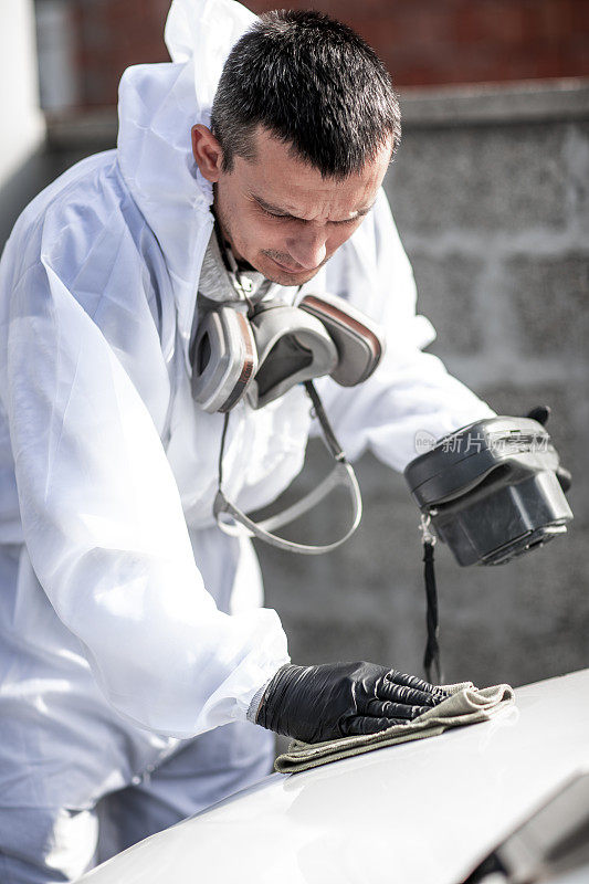汽车喷漆技师在用油漆检测装置测试表面之前，先用抹布清洗汽车的成品区域