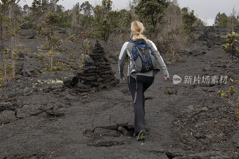 女性徒步旅行者沿着火山熔岩向前走