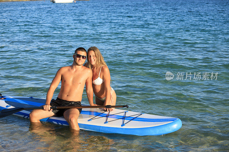 海滩度假年轻的夫妇，女人和男人划桨站立板SUP，海夏季爱