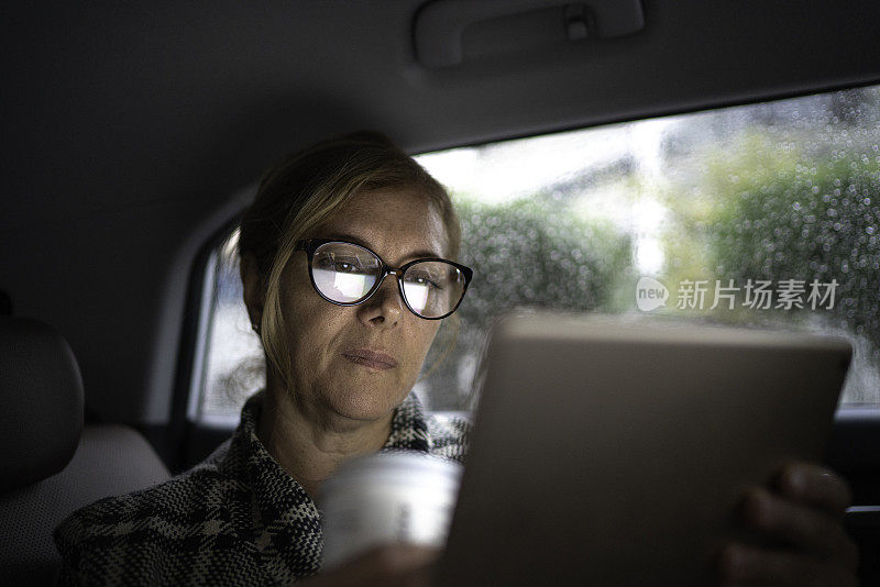 在出租车里工作的女人，用着平板电脑，喝着咖啡