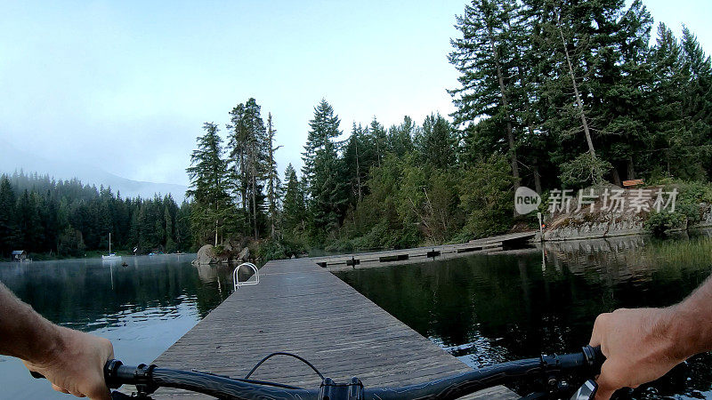 早上，一名男子沿着湖边的码头骑自行车