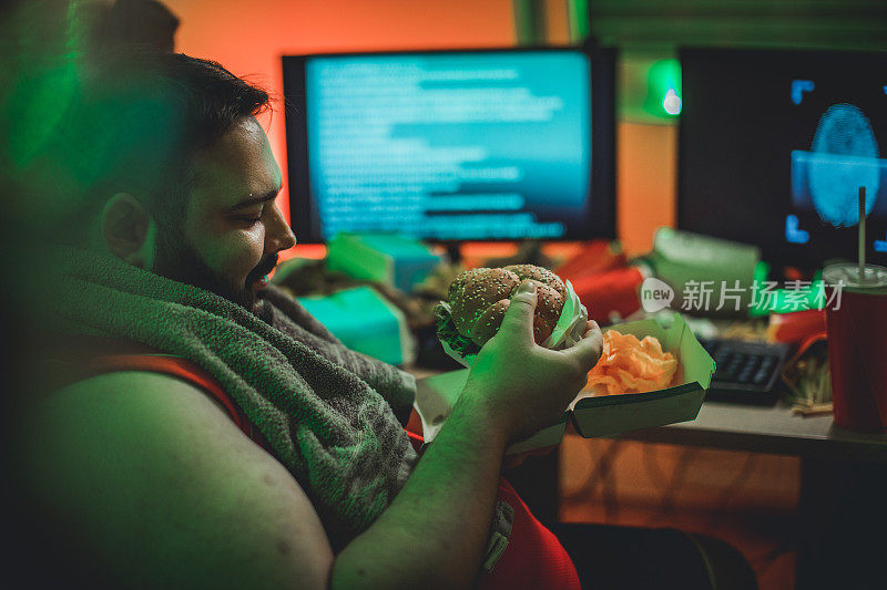一个人在电脑前吃着汉堡喝着苏打水