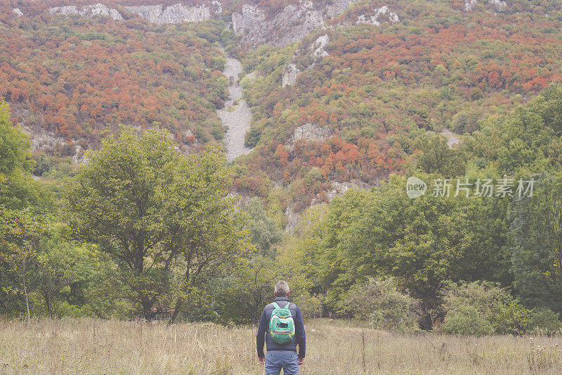 一名成年男子于秋日在美丽的山林中徒步旅行