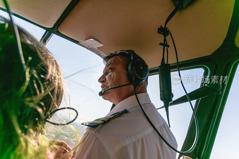 直升机飞行员戴着耳机与乘客一起飞行