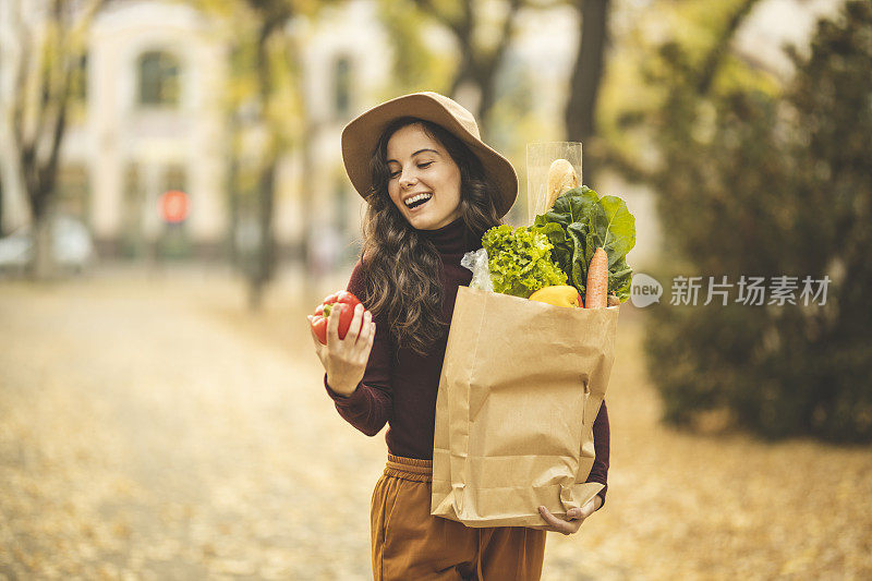 拿着装满杂货和胡椒的纸袋的女人