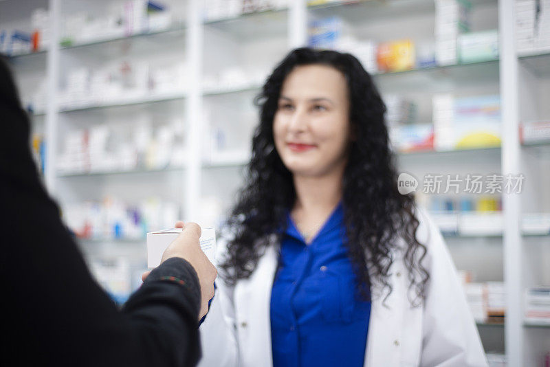 年轻女性药剂师在药店给年轻男子药物的肖像-不认识的人从女性药剂师那里得到药物