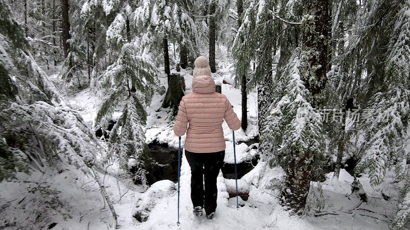 女性徒步旅行者沿着雪道行走