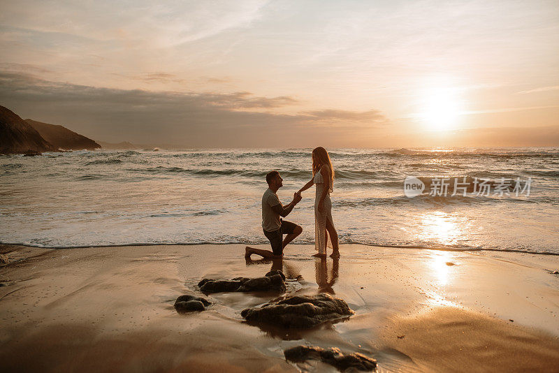 一个年轻人在海滩上向他的女朋友求婚