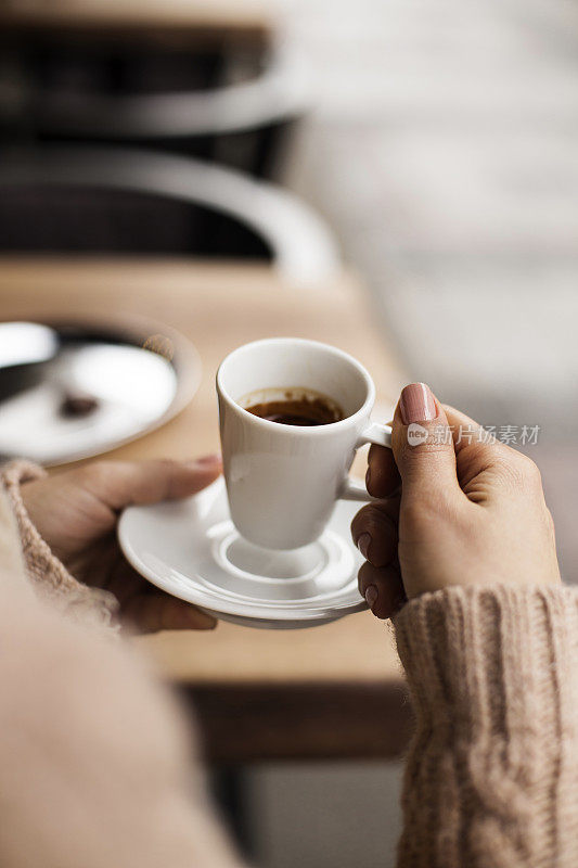 咖啡杯，女士的手拿着咖啡杯，女士拿着一个白色的杯子，咖啡在白色的杯子里