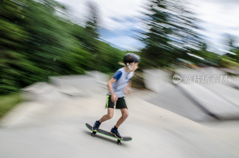 小男孩滑着滑板从斜坡上下来