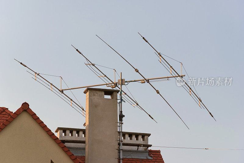 屋顶上的电视天线。屋顶广播电视和广播技术。信号接收器。传输媒体塔。带有模拟天线桅杆的住宅屋顶。城市摄影
