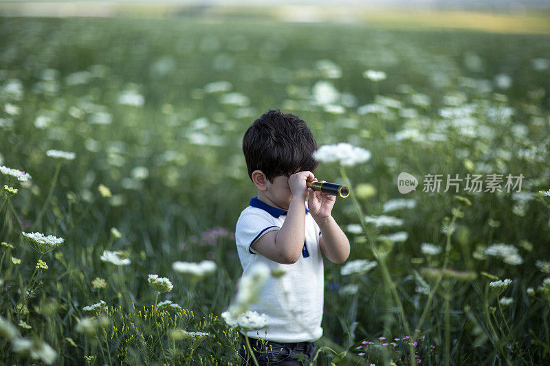 小男孩年轻的研究员抬起头，用双筒望远镜探索着