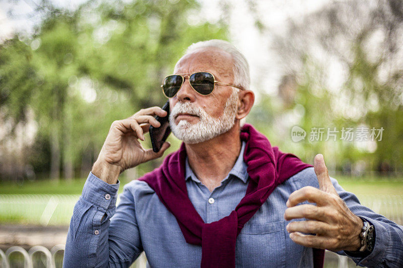 一个老人正在室外用手机打电话