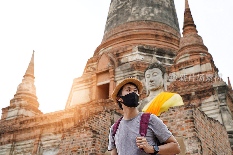 一名亚洲男子在前往泰国大城府旅游时戴着黑色面具微笑。佩戴防护口罩，预防新冠肺炎