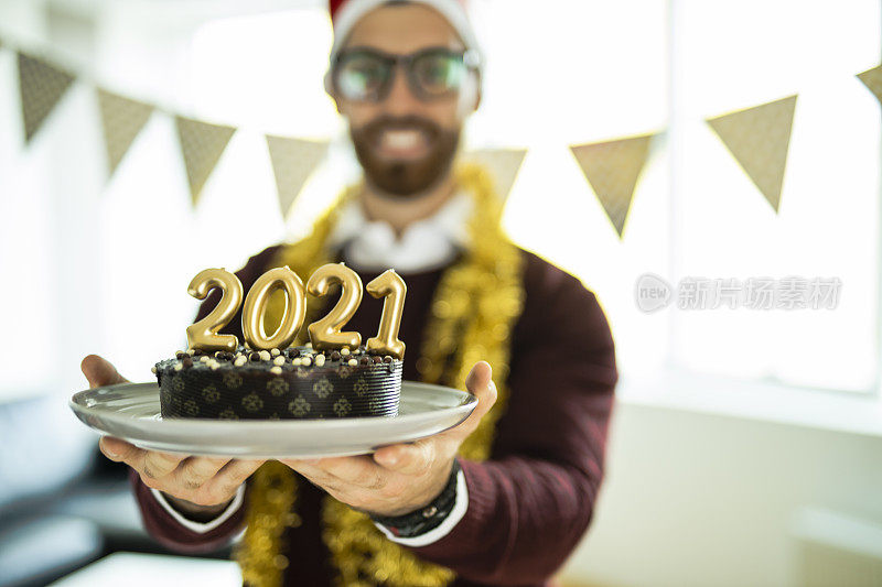 年轻女子在新年派对上玩得很开心，巧克力蛋糕上写着蜡烛数字2021，代表即将到来的新年