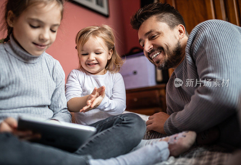单身年轻父亲和他的女儿在家里用电子平板电脑看书