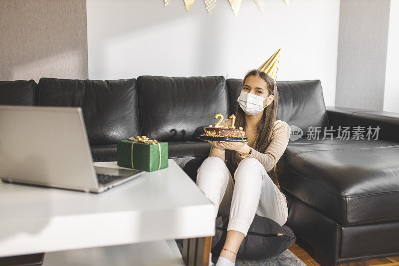 在新冠肺炎大流行期间，快乐的小女孩打开礼物，与朋友视频通话，庆祝自己的21岁生日