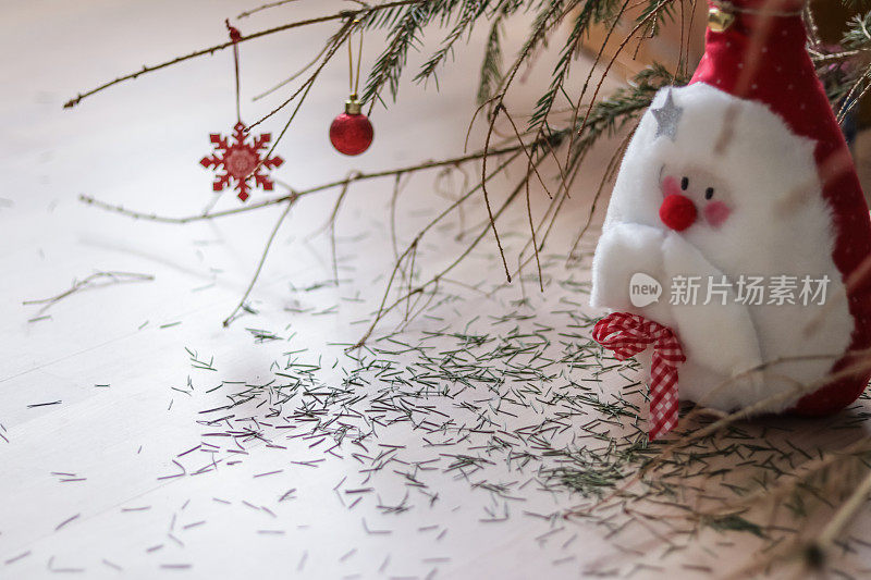 圣诞老人柔软的玩具在圣诞树下用松针摇摇欲坠。