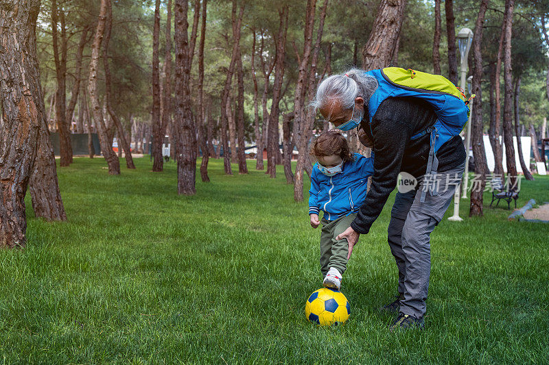 爷爷在公园里教孙子踢足球
