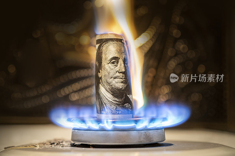 美元在大火中燃烧。燃气灶的背景是一百元。在美国汽油价格上涨的概念。昂贵的天然气供应