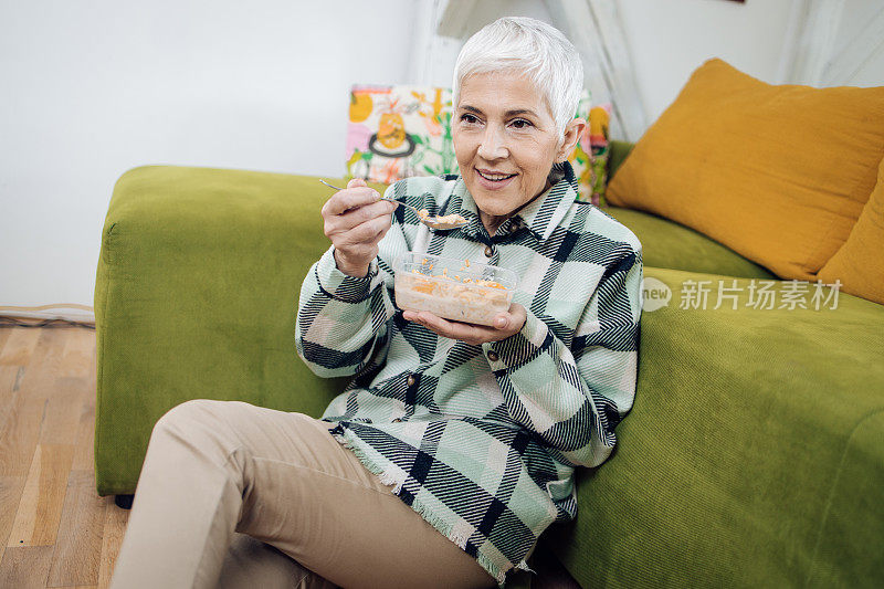 一个快乐成熟的女人从塑料盒子里吃早餐的肖像