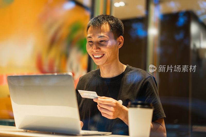 微笑的男人用信用卡支付笔记本电脑购物