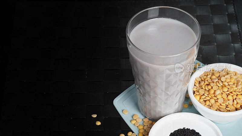黑芝麻和豆浆混合在透明玻璃上，黑芝麻和黄豆在一个杯子里。黑芝麻豆浆。健康饮料与天然成分。豆浆喝。
