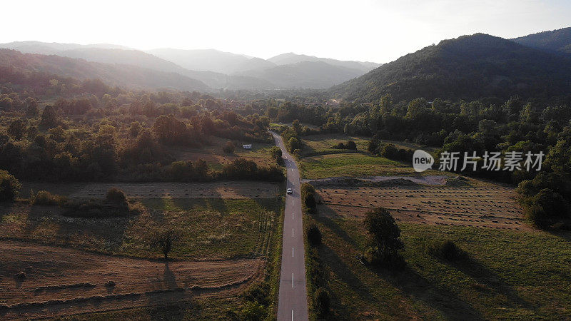 鸟瞰图，一辆红色的汽车沿着一条两侧是森林的道路行驶