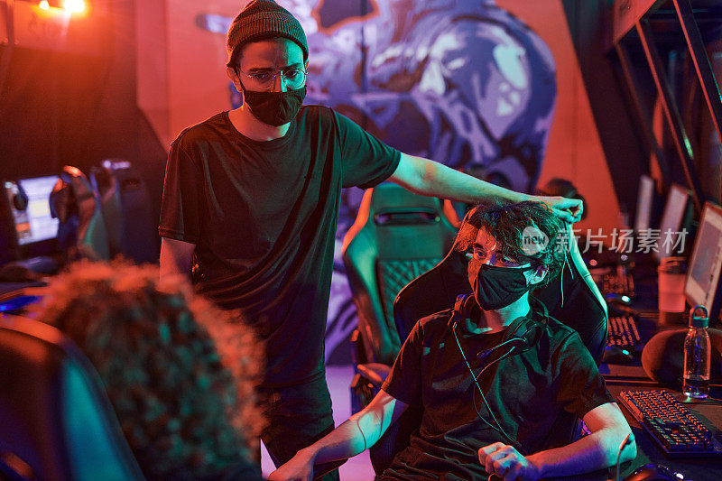 在电脑俱乐部比赛前，多种族的年轻游戏玩家戴着黑布面具，穿着t恤讨论策略