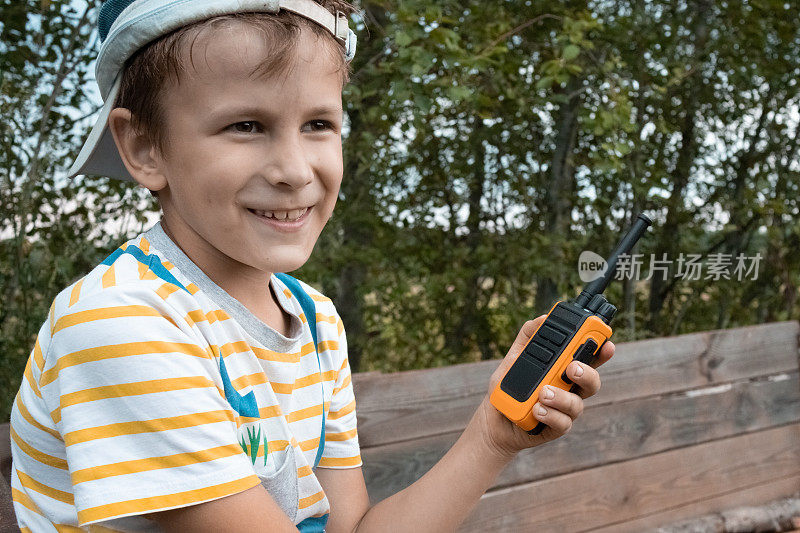 快乐的8岁男孩在公园外面玩对讲机