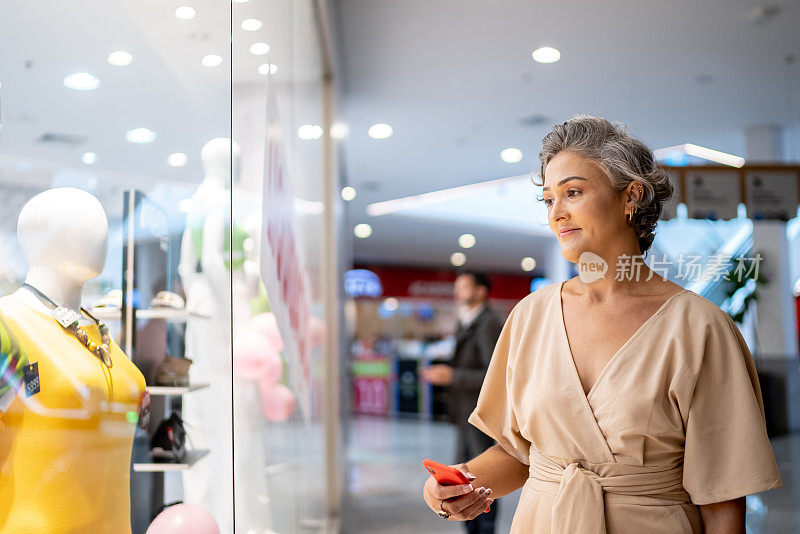 一个成熟的女人看着商场里的橱窗