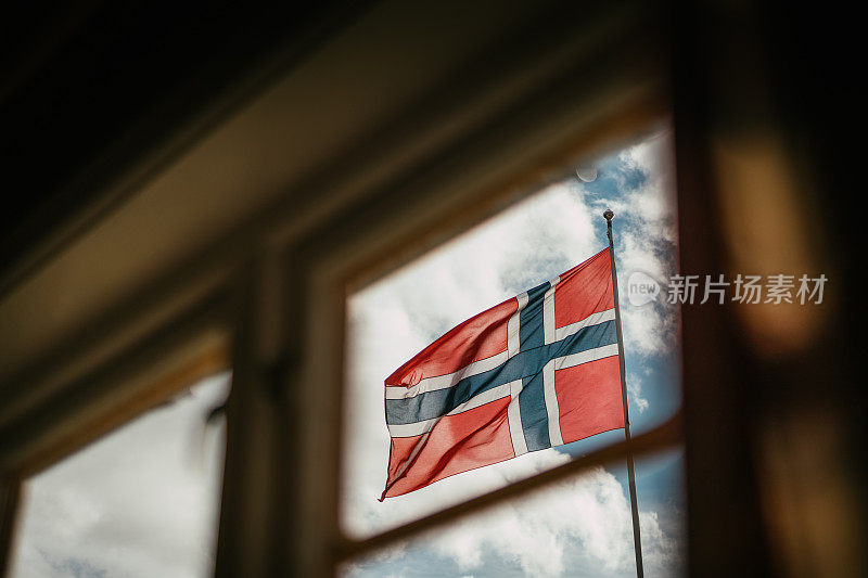 从窗口可以看到挪威国旗。在野外的北欧小木屋里