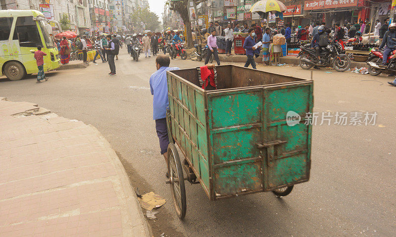 在市中心，一个拾荒者用他的三轮货车搬运废料。