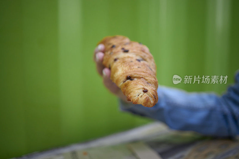 女人咬牛角面包户外酒吧早餐