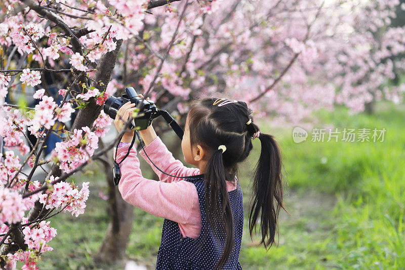 一个亚洲女孩用数码相机拍照。