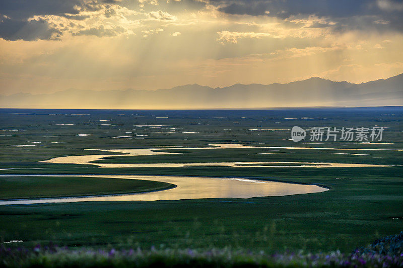 中国新疆维吾尔自治区，夕阳西下的草原上蜿蜒的河流