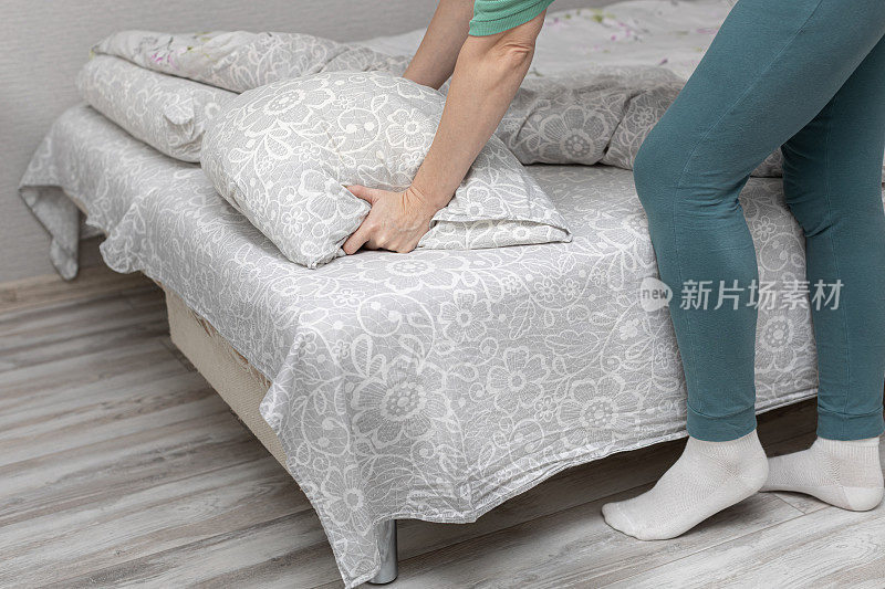 一个女人在家里用手拨弄躺在床上的枕头