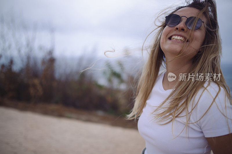 一个微笑的女人享受刮风的日子。