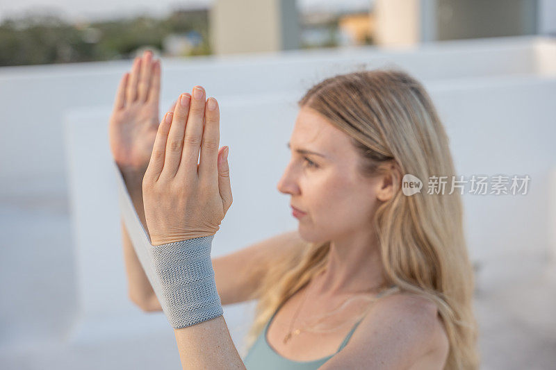 一个年轻女子在屋顶健身，她用了一个阻力带