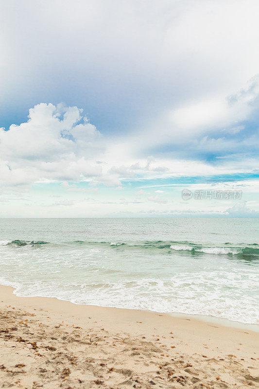 2022年9月，明亮的蓝色多云天空上的蓝绿色海浪横扫佛罗里达州海滨高地海滩