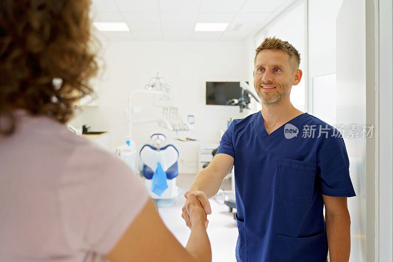 年轻的牙医正在和病人握手。