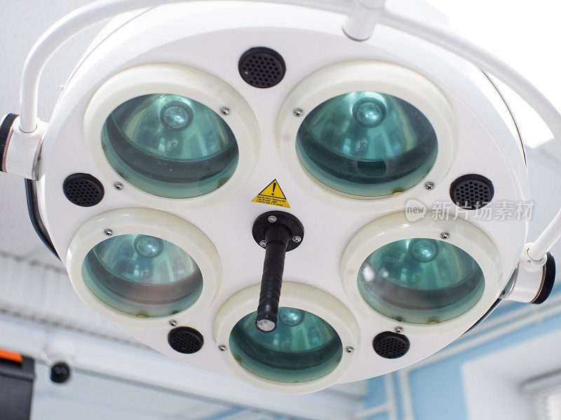 手术室的天花板上悬挂着一盏电动手术灯。手术灯安装在手术室的桌子上方。特写镜头。手术设备概念。