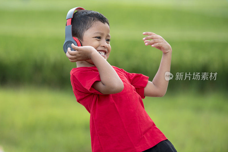 蹒跚学步的男孩用耳机听音乐