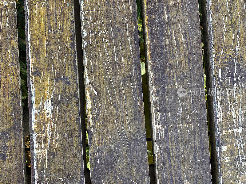 风化的硬木栅栏板的全帧图像，未经处理的木板与肮脏的木纹和缝隙，重点在前景