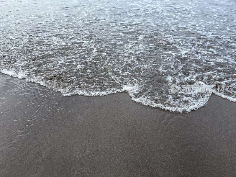 柔软的海浪和黑色的沙滩