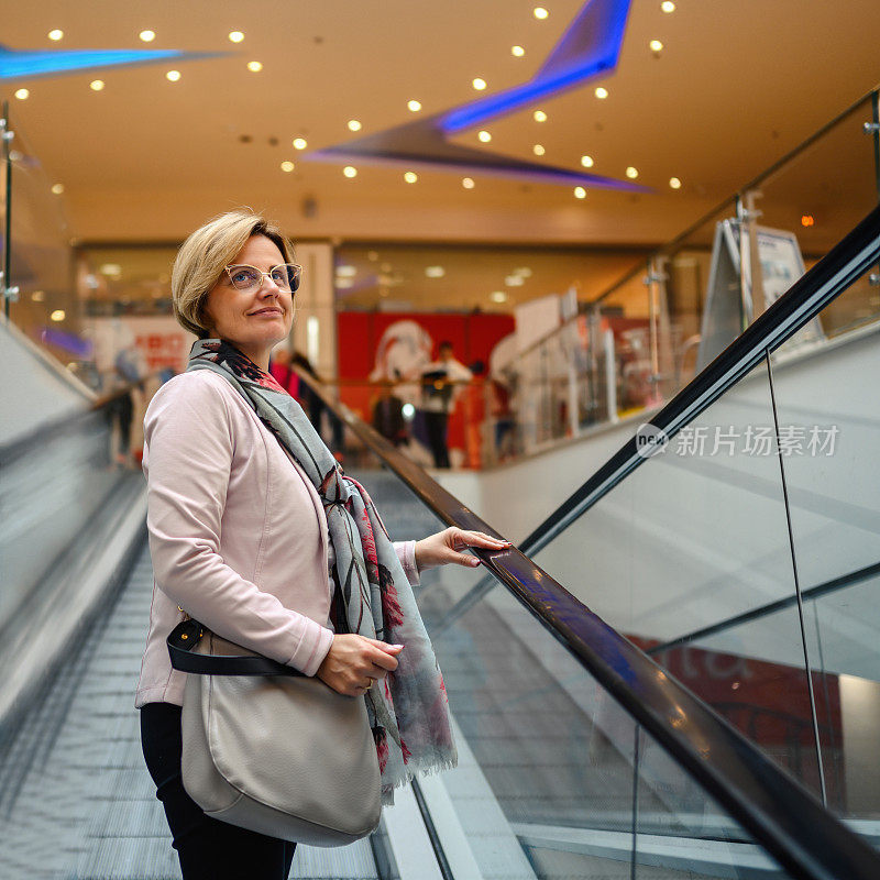 购物中心自动扶梯上的女人。