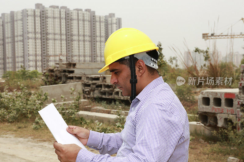 自信的建筑师在工地检查蓝图。