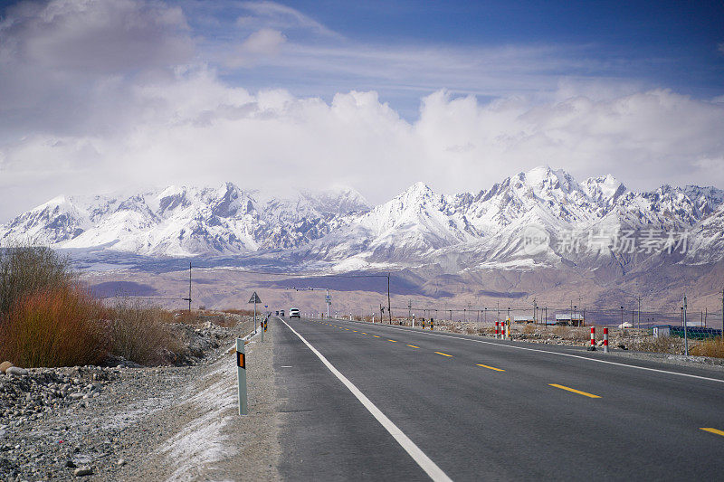 雪山背景公路位于帕米尔山区，空旷的柏油路配雪山