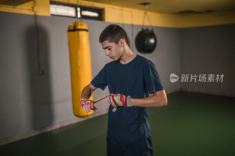 专注的年轻人在戴上拳击手套之前用一块布包裹双手，这有助于减少拳击对手时的冲击力，并有助于防止拳击受伤